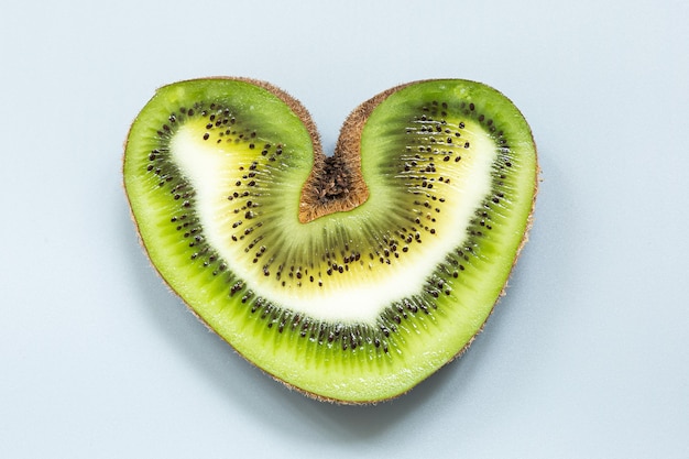 Foto kiwi feo en forma de corazón en un corte sobre un fondo gris.