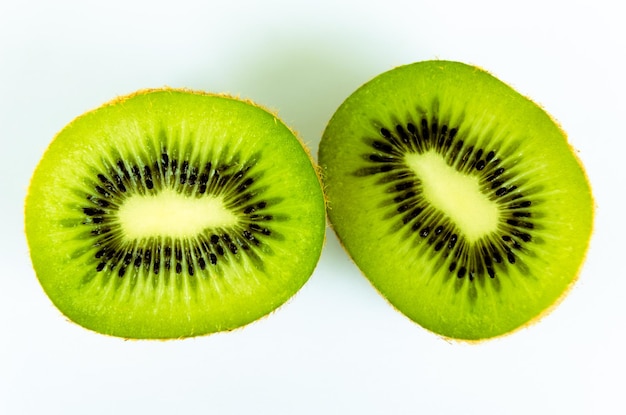 Kiwi fresco aberto ao meio sobre fundo branco e as sementes dentro da fruta