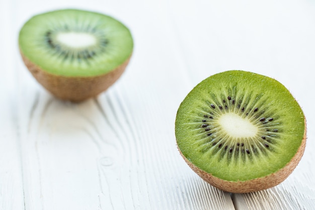 Kiwi fresco cortado por la mitad en una mesa blanca de madera Vista frontal