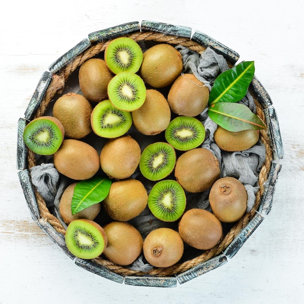 Kiwi fresco y hojas verdes en una caja de madera sobre el fondo antiguo Frutas Vista superior Espacio libre para texto