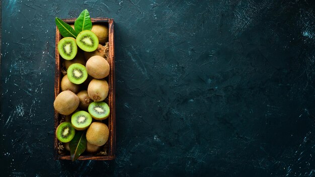 Kiwi fresco y hojas verdes en una caja de madera sobre el fondo antiguo Frutas Vista superior Espacio libre para texto