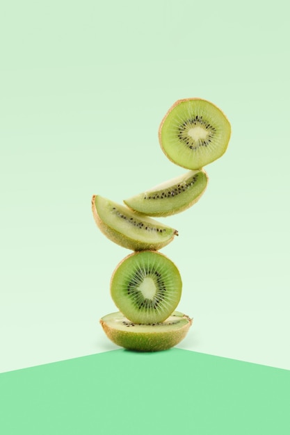 Kiwi-Frucht-Food-Balance auf grünem geometrischen Papier-Hintergrund veganer Ausgleich kreatives Lebensmittelkonzept