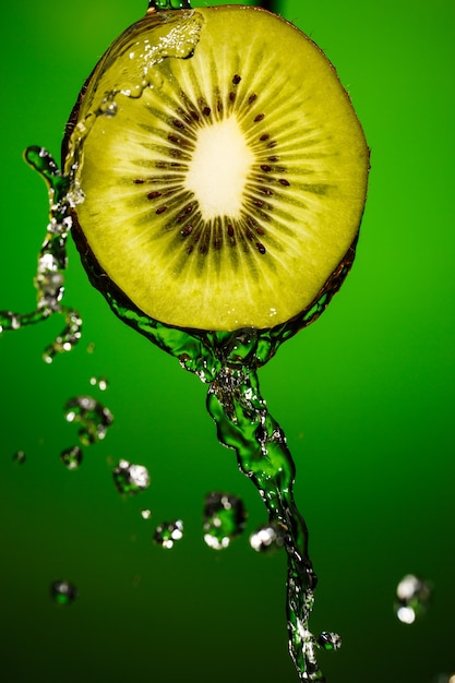 Kiwi im Spritzwasser isoliert auf grünem Hintergrund