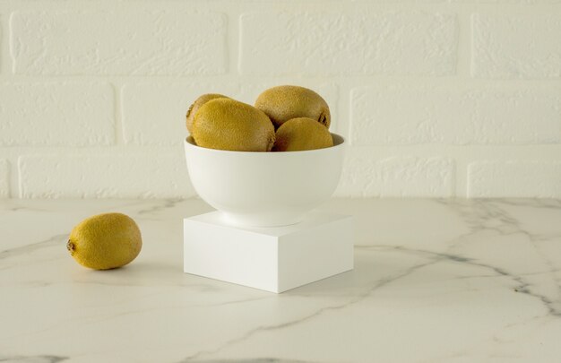 Kiwi in einer weißen Schüssel auf einem Podium oder einem Marmorküchentisch. Frische saftige tropische Früchte.