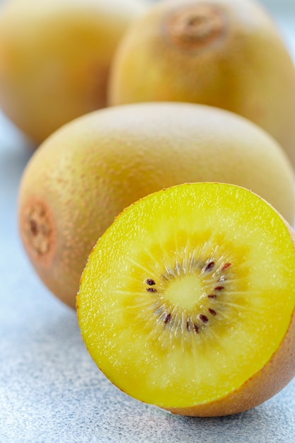 Kiwi orgánico dorado, frutas jugosas maduras enteras y cortadas en gris