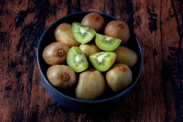 Kiwi en un plato de cerámica azul sobre una mesa de madera antigua