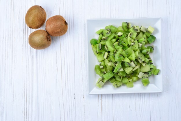 Kiwi recién cortado con kiwis enteros en segundo plano.