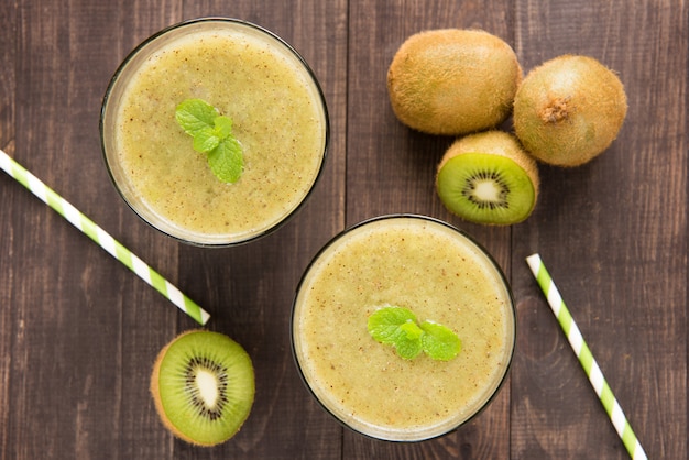 Kiwi Smoothie mit frischen Früchten auf hölzernem Hintergrund. Ansicht von oben