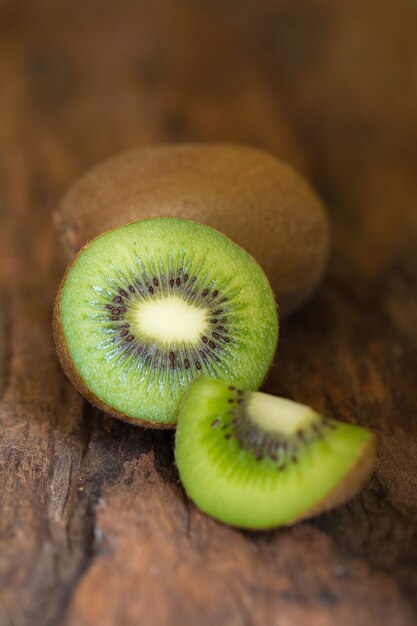 Kiwi und halbe Kiwi auf hölzernem Hintergrund, selektiver Fokus