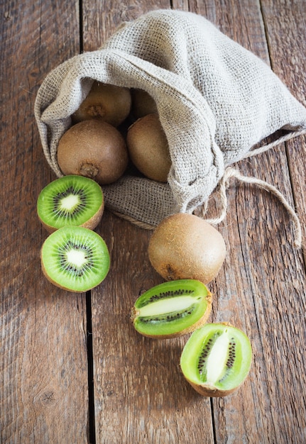 Kiwis frescos no saco na superfície de madeira marrom