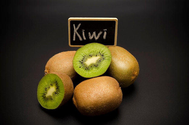 Kiwis y placa con la inscripción kiwi sobre fondo negro