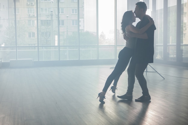 Kizomba-Tänzer zeigen ihre Leidenschaft für das Tanzen von Kizomba vor einem Tanzraum mit großen Fenstern im Hintergrund. Leidenschaftliche Tänzer.