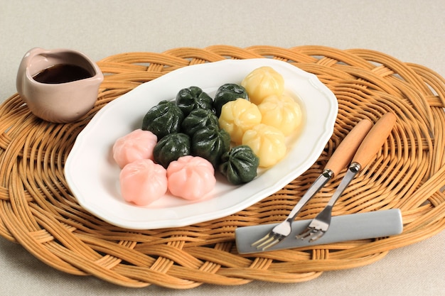 Kkultteok de três cores é bolo de arroz em forma de bola cheio de mel e xarope de gergelim, bolo tradicional coreano para o dia de Chuseok. Servido em Prato Branco