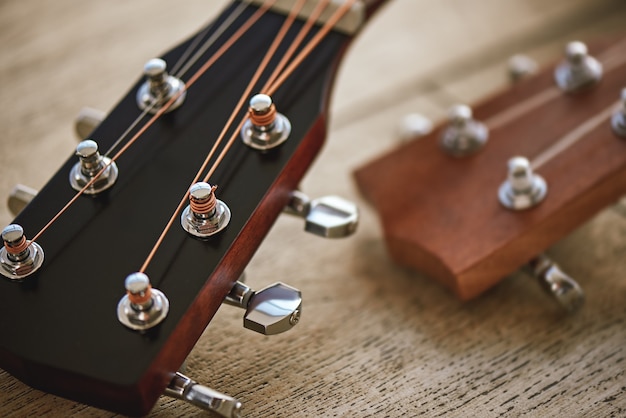 Klanganpassung. Nahaufnahme Foto von Gitarrenhälsen mit Stimmschlüsseln zum Einstellen der Saiten vor Holzhintergrund. . Musikanlage. Musikinstrumente. Musikkonzept