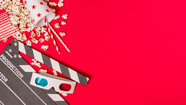 Klappe; Popcorn- und Mitnehmerglas mit Trinkhalmen und Popcorn auf rotem Hintergrund