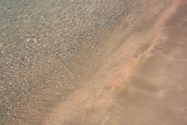 Klare Wellen und bunter Sand am tropischen Sandstrand in Kreta Griechenland.