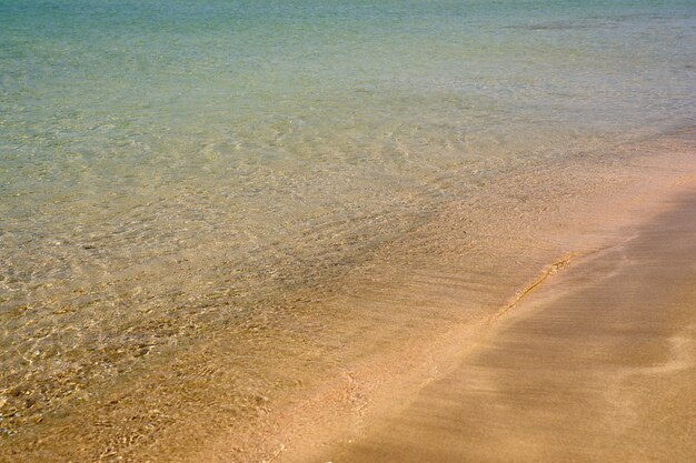 Klare Wellen und bunter Sand am tropischen Sandstrand in Kreta Griechenland.