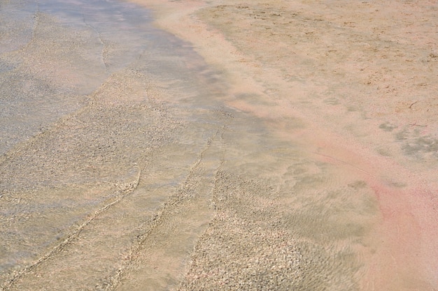 Klare Wellen und bunter Sand am tropischen Sandstrand in Kreta Griechenland.