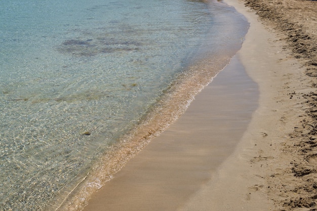 Klare Wellen und bunter Sand am tropischen Sandstrand in Kreta Griechenland.