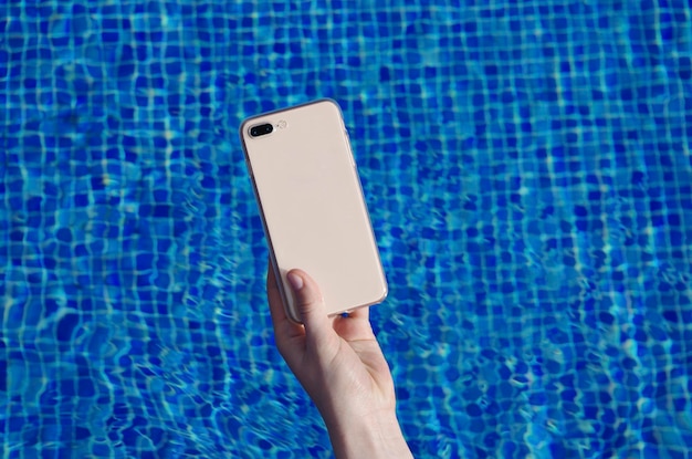 Klares Handyhüllenmodell in der Hand auf dem Hintergrund der Rückansicht des Swimmingpool-Smartphones