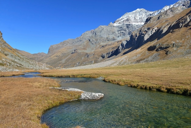 Klares Wasser eines Flusses, der alpinen Berg mit schneebedeckten Spitzen kreuzt