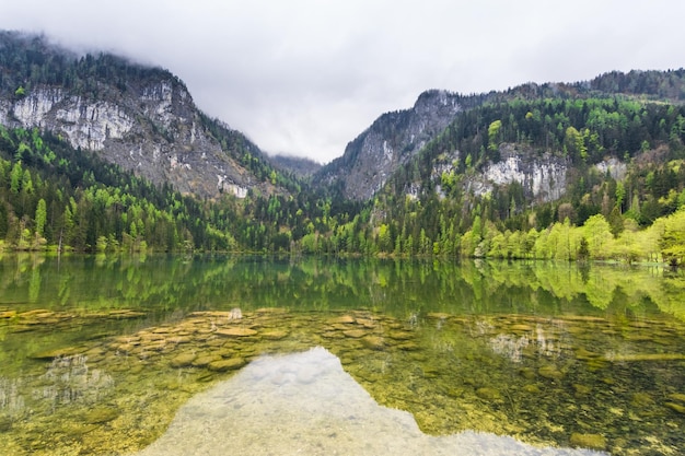 klares Wasser mit Steinen und Spiegelungen aus den Bergen