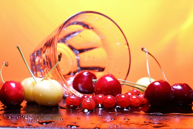 Klarglasbecher mit Kirschen auf einem getönten Hintergrund Nahaufnahme von Beeren mit Wassertropfen