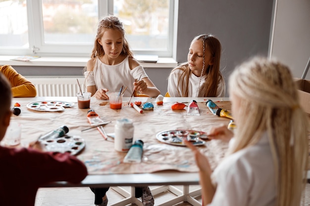 Klassenkameraden malen auf Papier mit bunten Farben