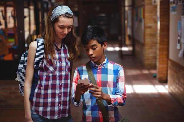 Klassenkameraden mit Handy im Korridor in der Schule