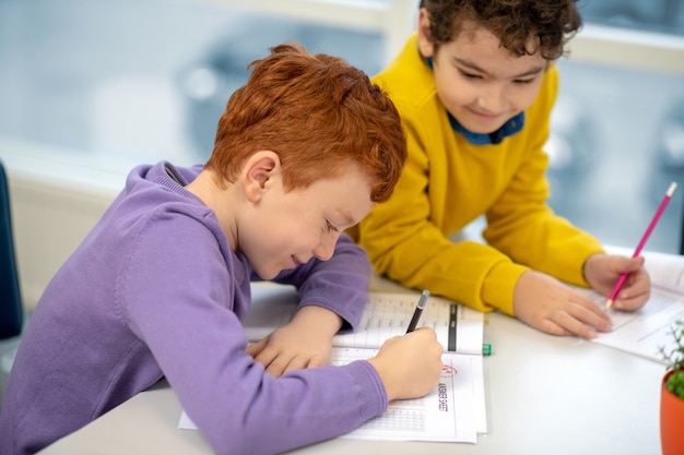 Klassenkameraden schauen sich ihre Hefte an und schreiben