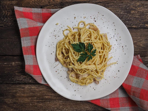 Klassische hausgemachte Pasta-Carbonara-Spaghetti mit Speck, Eigelb, Petersilie und Parmesankäse auf hellem Hintergrund