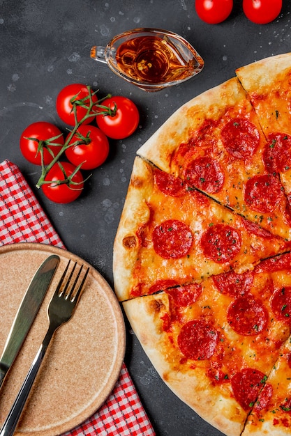 Klassische italienische Peperoni-Pizza und leerer Teller, Draufsicht, vertikales Foto. Hochwertiges Foto