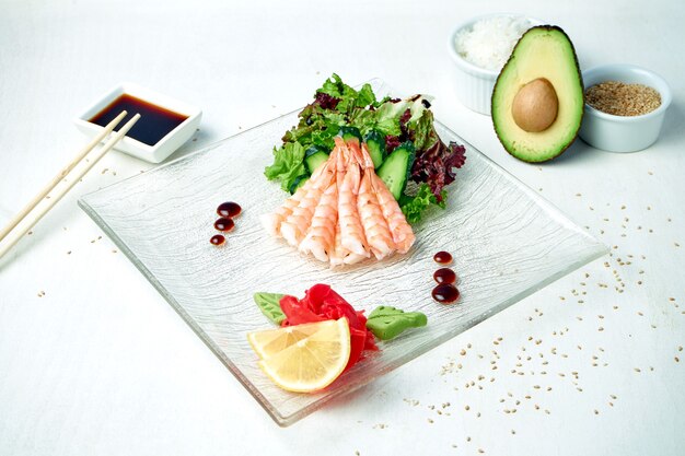 Klassische japanische Sashimi - Garnelen mit Salat auf einem weißen Teller in einer Komposition mit Zutaten
