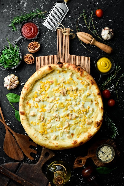 Klassische Pizza mit Huhn, Ananas und Käse Käse-Pizza auf schwarzem Steinhintergrund