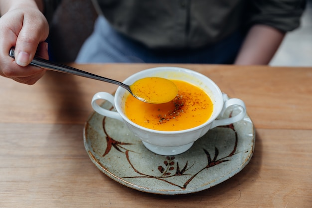 Klassische pürierte kürbissuppe mit pfeffer von hand übergießen.