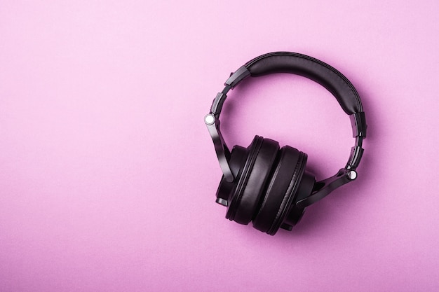 Klassische schwarze kabellose Kopfhörer auf rosa minimalem Hintergrund