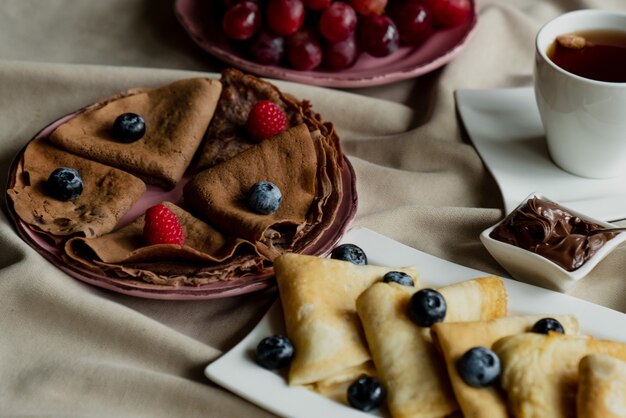 Klassische und Schokoladenpfannkuchen mit Beeren und Früchten zum Frühstück, Schokolade, Tee,