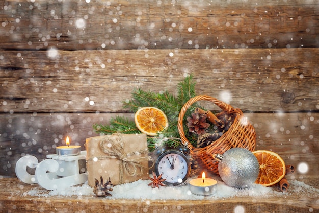 Foto klassische weihnachtskomposition winterobjekte wecker geschenkbox korb tannenzweig ornamente auf holzuntergrund. weihnachten neujahr weihnachten dezember banner. zeit für feierkonzept.