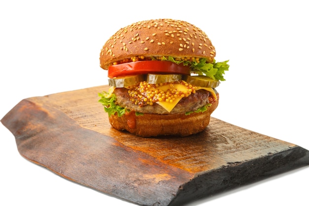 Klassischer Burger mit Rindfleisch, Käsegemüse in Soße auf einem Brötchen mit Sesam auf einem Holzbrett auf einem weißen Hintergrund. Horizontales Foto