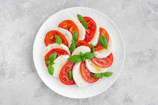 Klassischer Caprese-Salat mit Mozzarella-Käse-Tomaten und Basilikum auf einem weißen Teller o