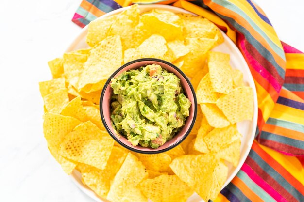 Klassischer Guacamole-Dip in einer kleinen Schüssel mit Maistortilla-Chips.