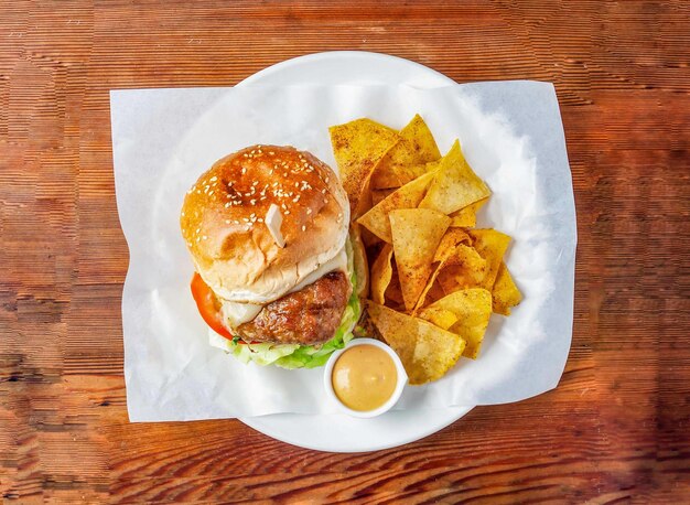 Klassischer Hühnerburger mit Gurken, Tomaten und Kohl, Mayonnaise-Dip und Cracker, serviert in einem Gericht, isoliert auf einem hölzernen Tisch, Blick auf das Essen in Hong Kong