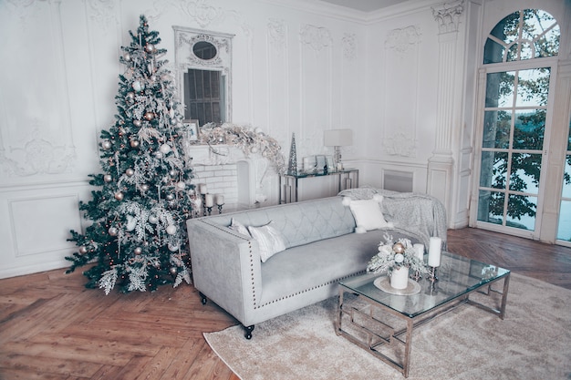 Klassischer Innenraum der weißen Weihnacht mit modernen Elementen und Baum des neuen Jahres verziert.