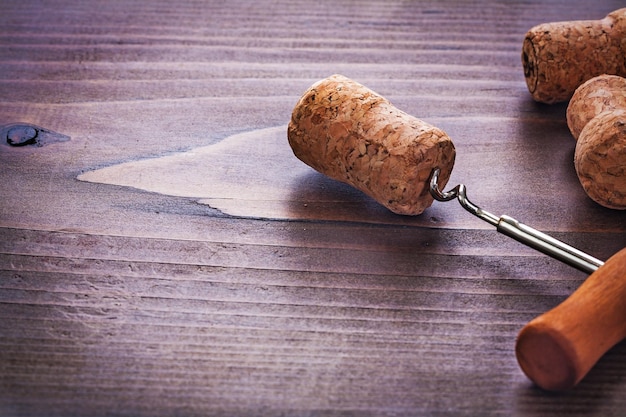 Klassischer Korkenzieher in Champagnerkorken auf Vintage-Holzbrett-Alkoholkonzept verdreht