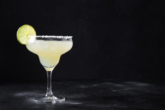 Klassischer Margarita-Cocktail mit Limettensaft und Eiswürfel auf schwarzem Hintergrund