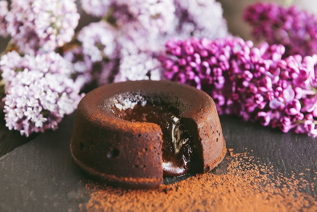 Klassischer Schokoladenfondant auf dunklem Hintergrund mit Blumen