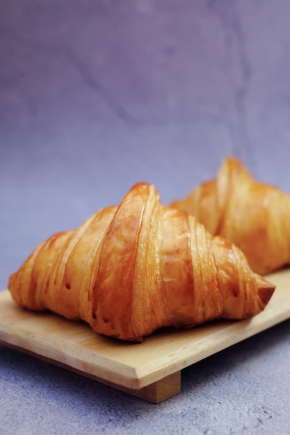 Klassisches Croissant der Nahaufnahmebutter auf Holzteller