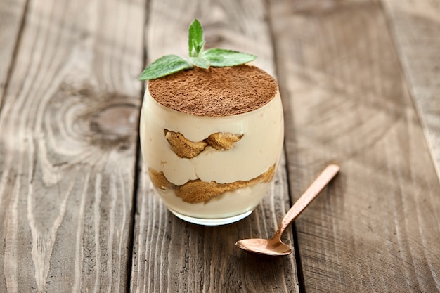 Klassisches Dessert Tiramisu in einem Glas auf einem Holzbrett an einem sonnigen Tag