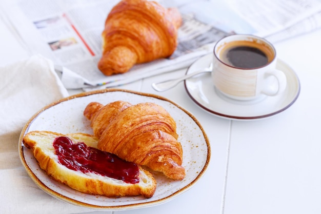 Klassisches französisches Frühstück mit Croissant mit Marmeladenkaffee und Zeitung