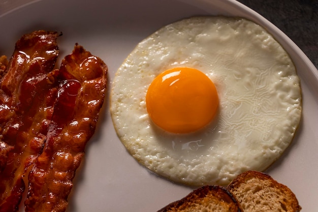 klassisches Frühstücksgericht mit goldgelben, knusprigen Speckstreifen und perfekt geröstetem Brot